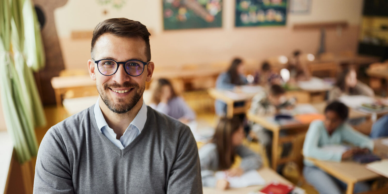 Teacher in glasses smiling in front of class of students