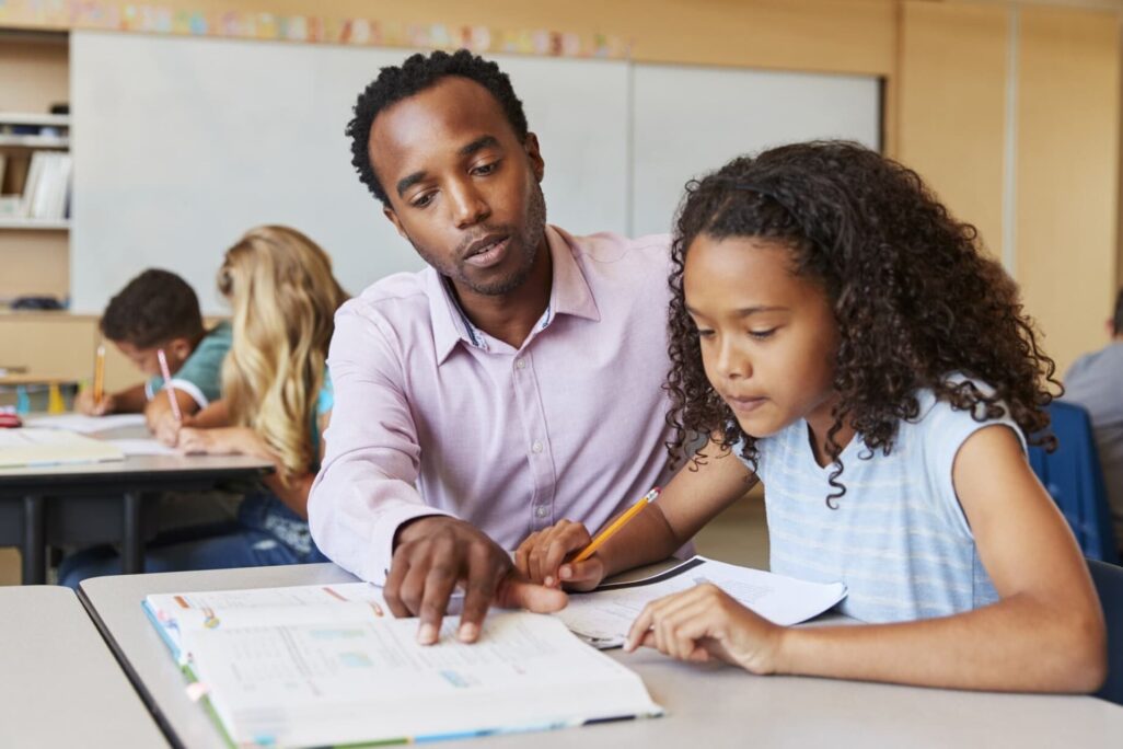 educator helping elementary student with classwork