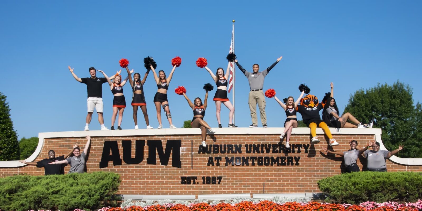 Group of students standing on top of Auburn University at Montgomery sign