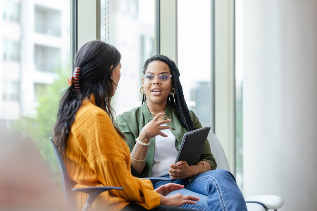 Psychology program student holding tablet and discussing class with classmate